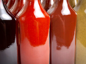 Vista de cerca de varias botellas de vidrio llenas de varios tipos de salsas picantes.